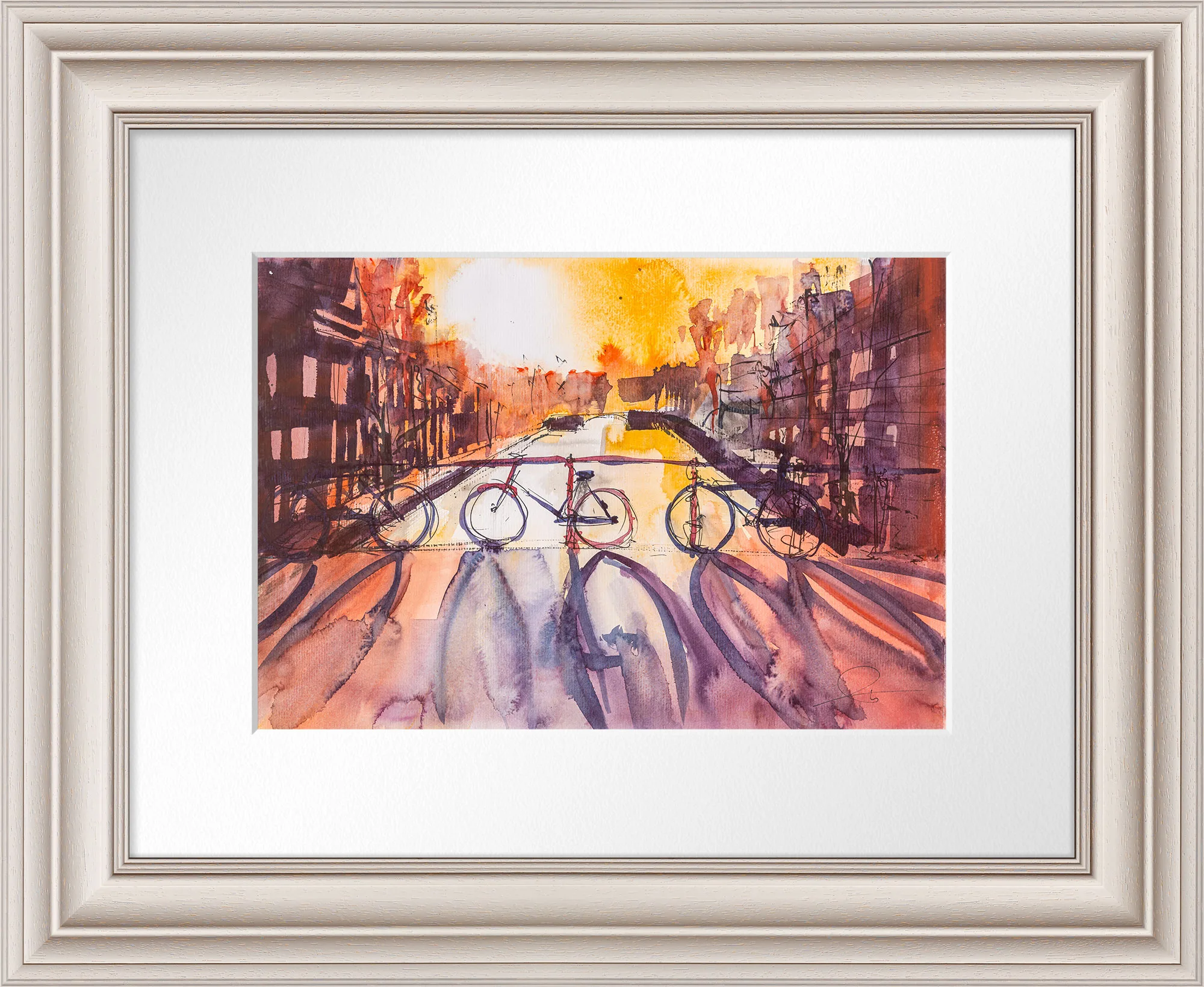 Amsterdam Ambiance, an original watercolour and ink painting by Paul Kenton, shown in a cream frame with a white mount. A canal street glows orange at sunset, with three bicycles parked along the railing and long purple shadows.
