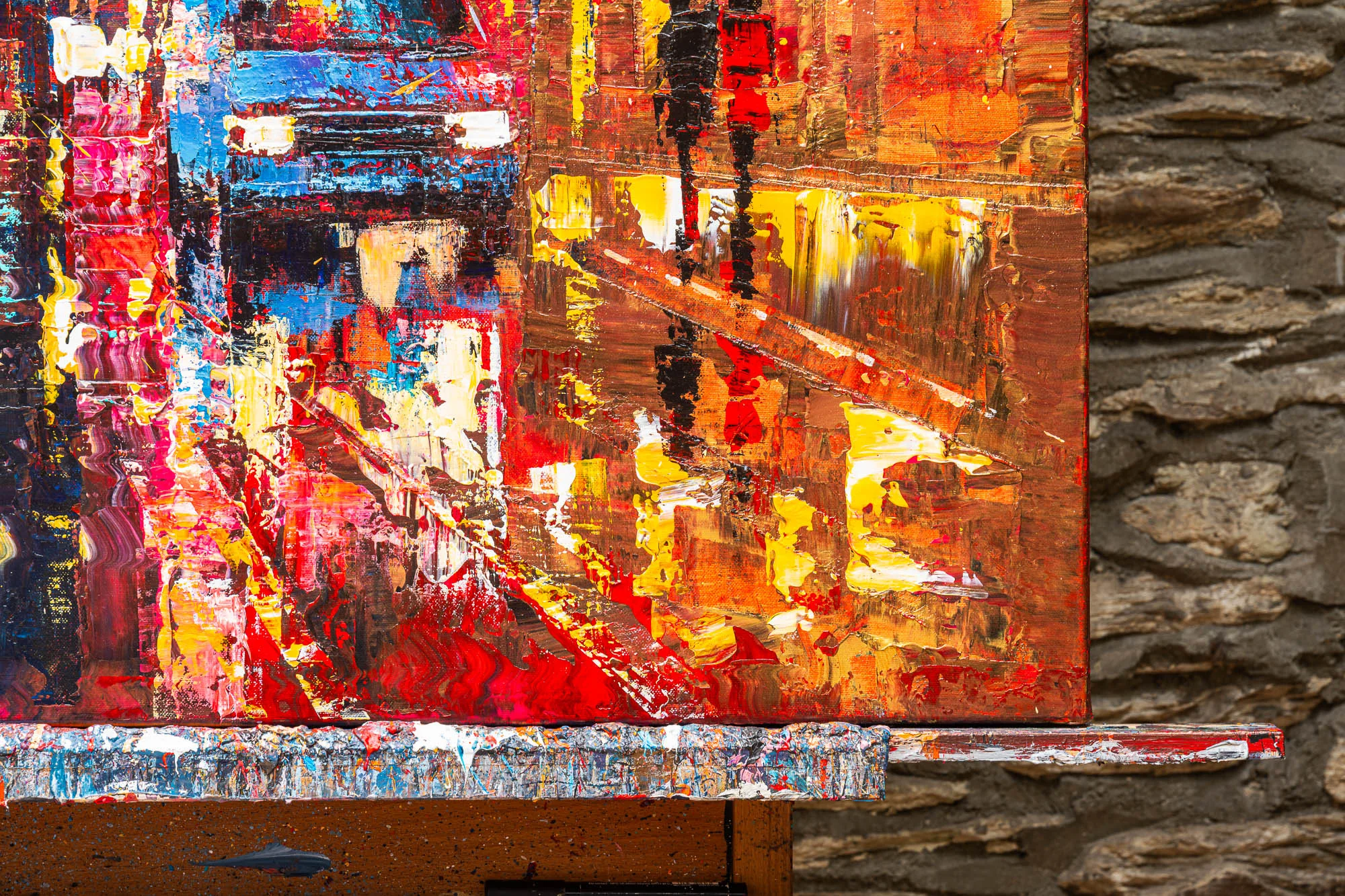 Close-up of Blazing Broadway, an original painting by Paul Kenton: thick, textured strokes of red, orange and yellow with glowing blue and metallic accents suggest a New York street lit at night.