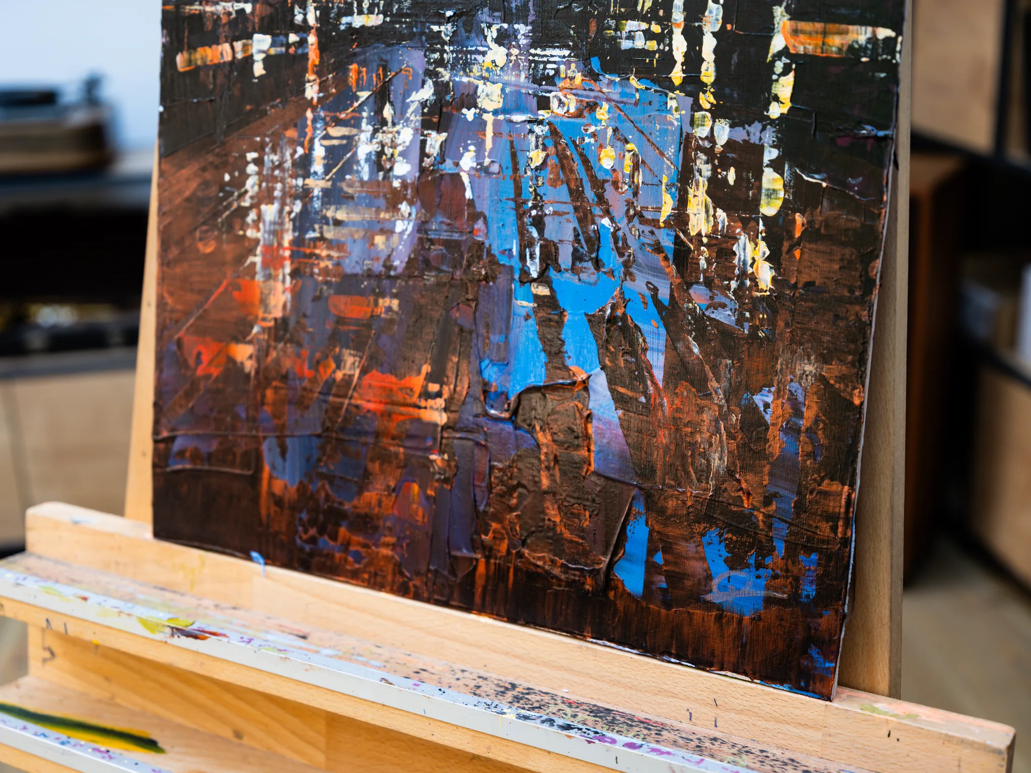 Close-up of Bridge Nocturne, an original painting by Paul Kenton, showing thick textured brushwork of brown, black and orange with flashes of bright blue and cream suggesting city lights at night.