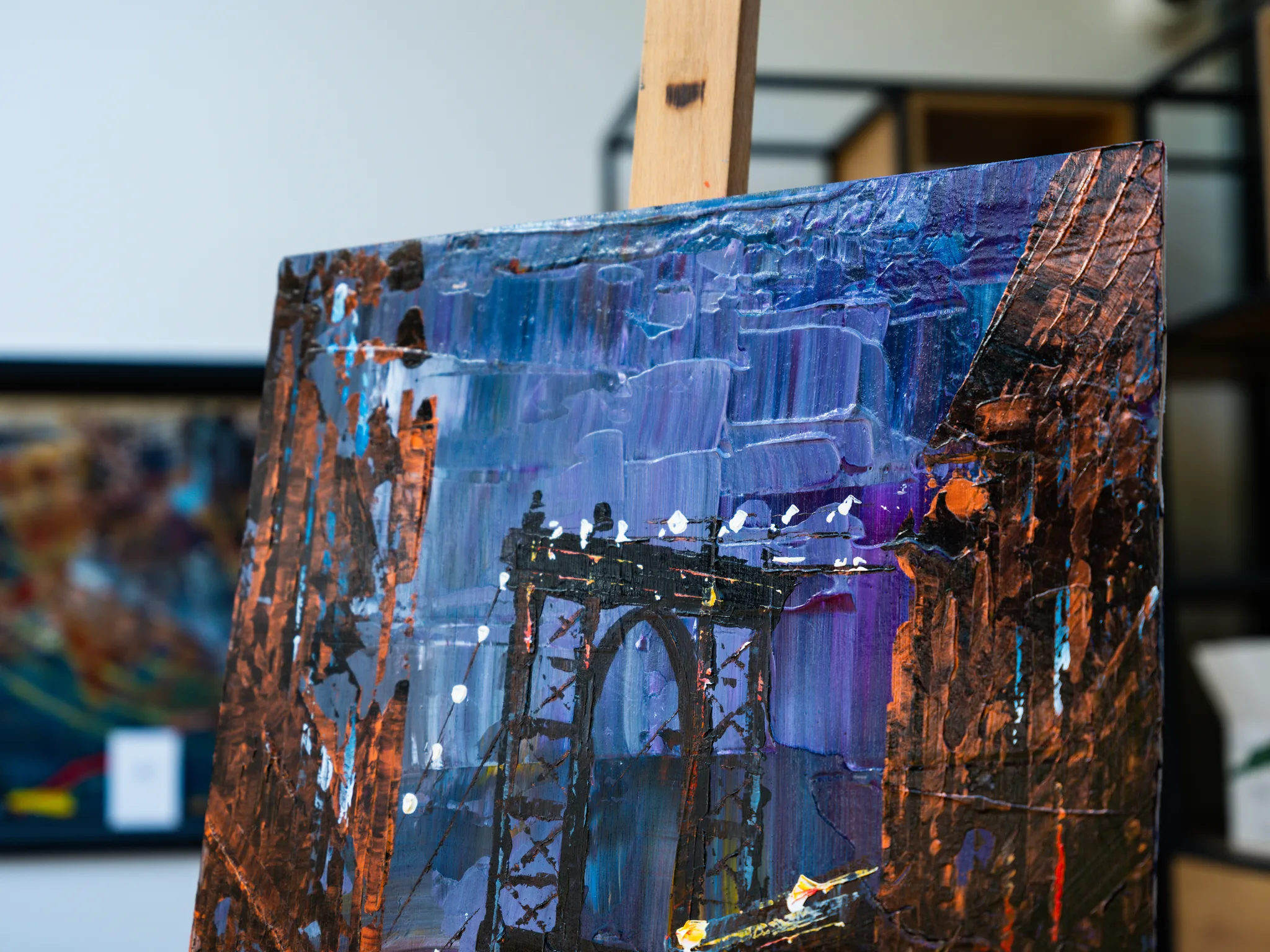 Close-up of Bridge Nocturne, an original mixed media painting by Paul Kenton: thick blue and violet brushstrokes frame a dark steel bridge arch, with copper-coloured textured edges.