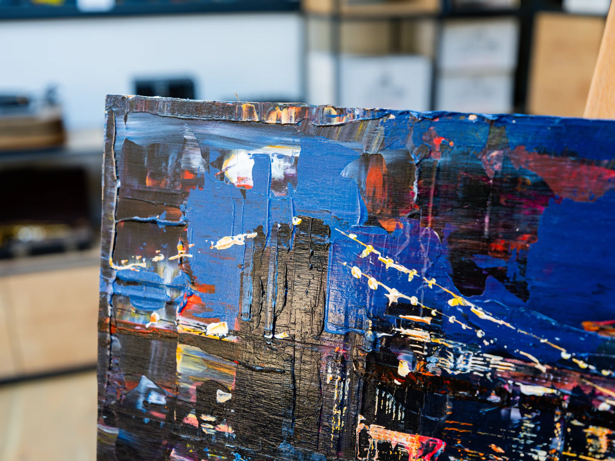 Close-up of City After Dark, an original painting by Paul Kenton: thick textured blues, black and red brushwork with flecks of white and gold, suggesting city lights at night.