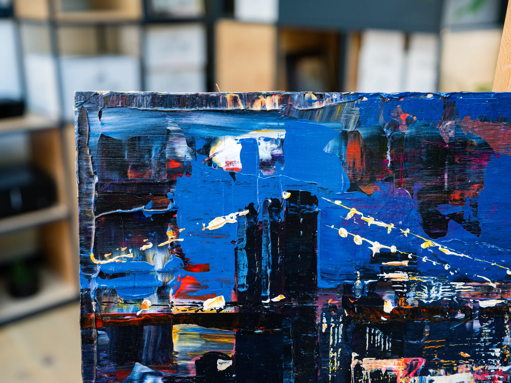 Close-up of City After Dark, an original painting by Paul Kenton: thick blue, black and red brushstrokes with flecks of gold metallic paint suggesting city lights at night.