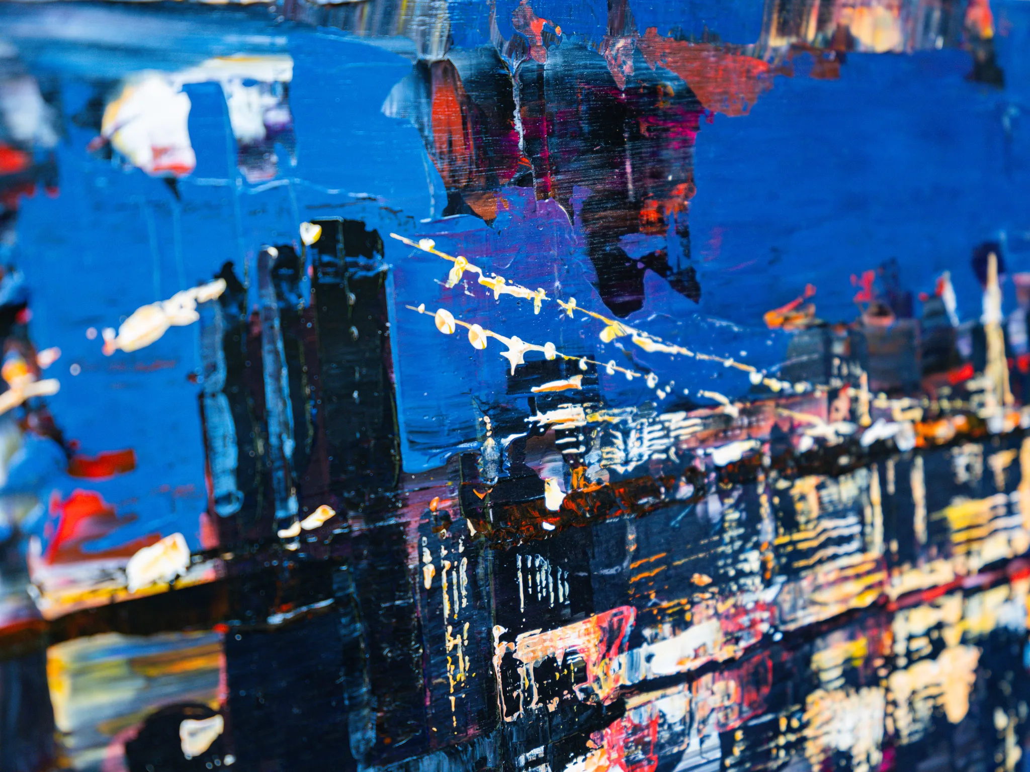 Close-up of City After Dark, an original painting by Paul Kenton: thick textured strokes of blue, black and gold depict dark city blocks with flecks of orange and white light.