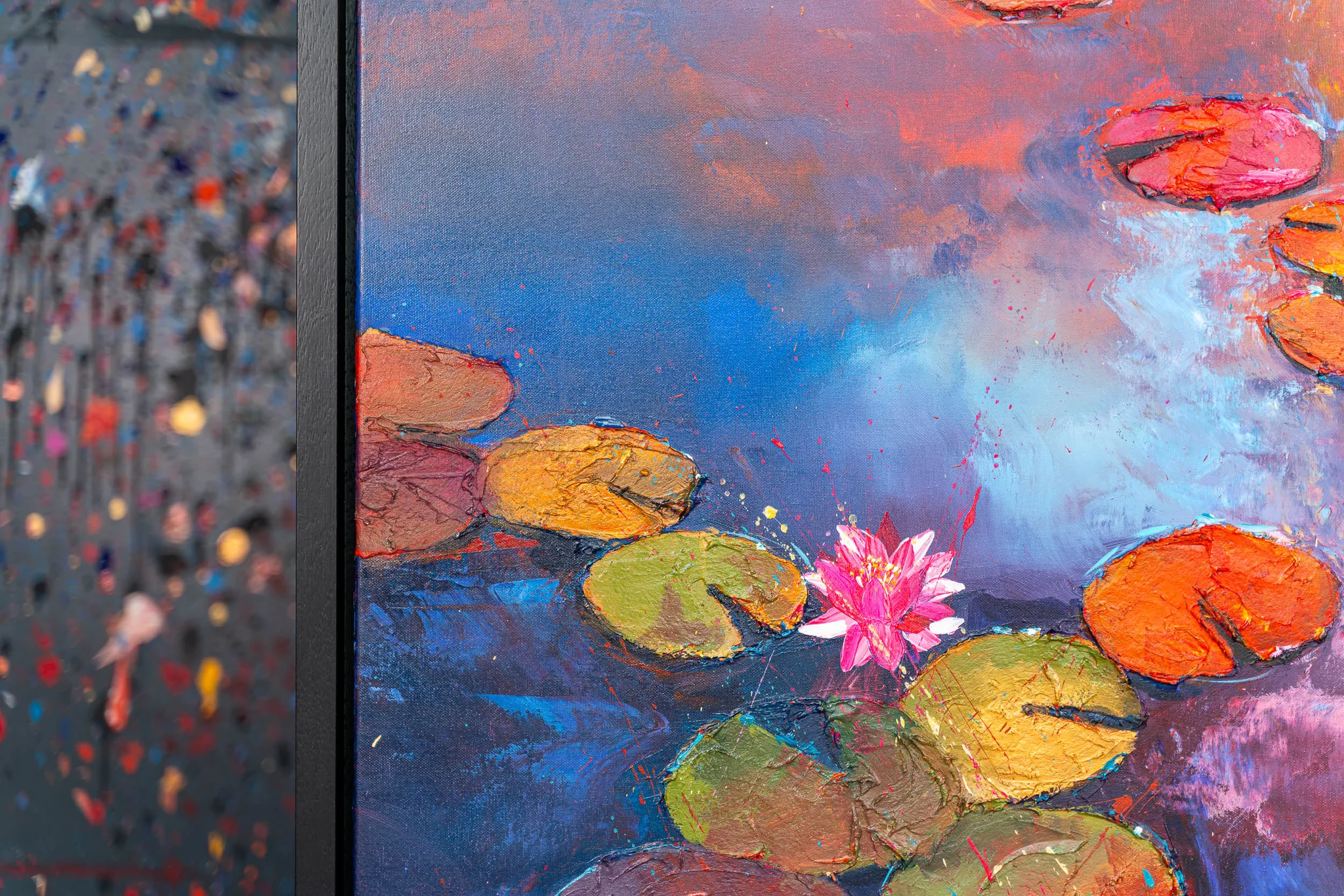 Close-up of Celestial Blooms, an original painting by Paul Kenton: thickly textured water lilies and a pink lotus bloom on deep blue water beneath a fiery orange and violet sky.