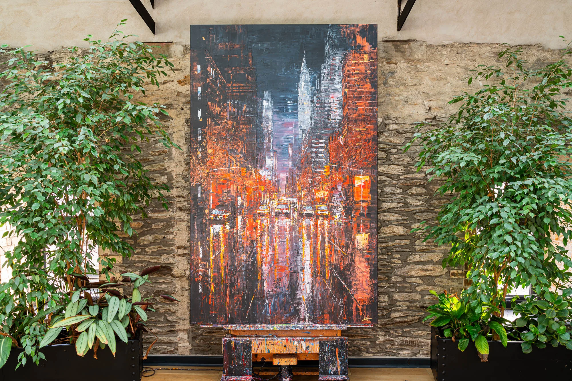 Embers of the City, an original painting by Paul Kenton: a tall New York street at night, glowing orange, hung on a stone wall.