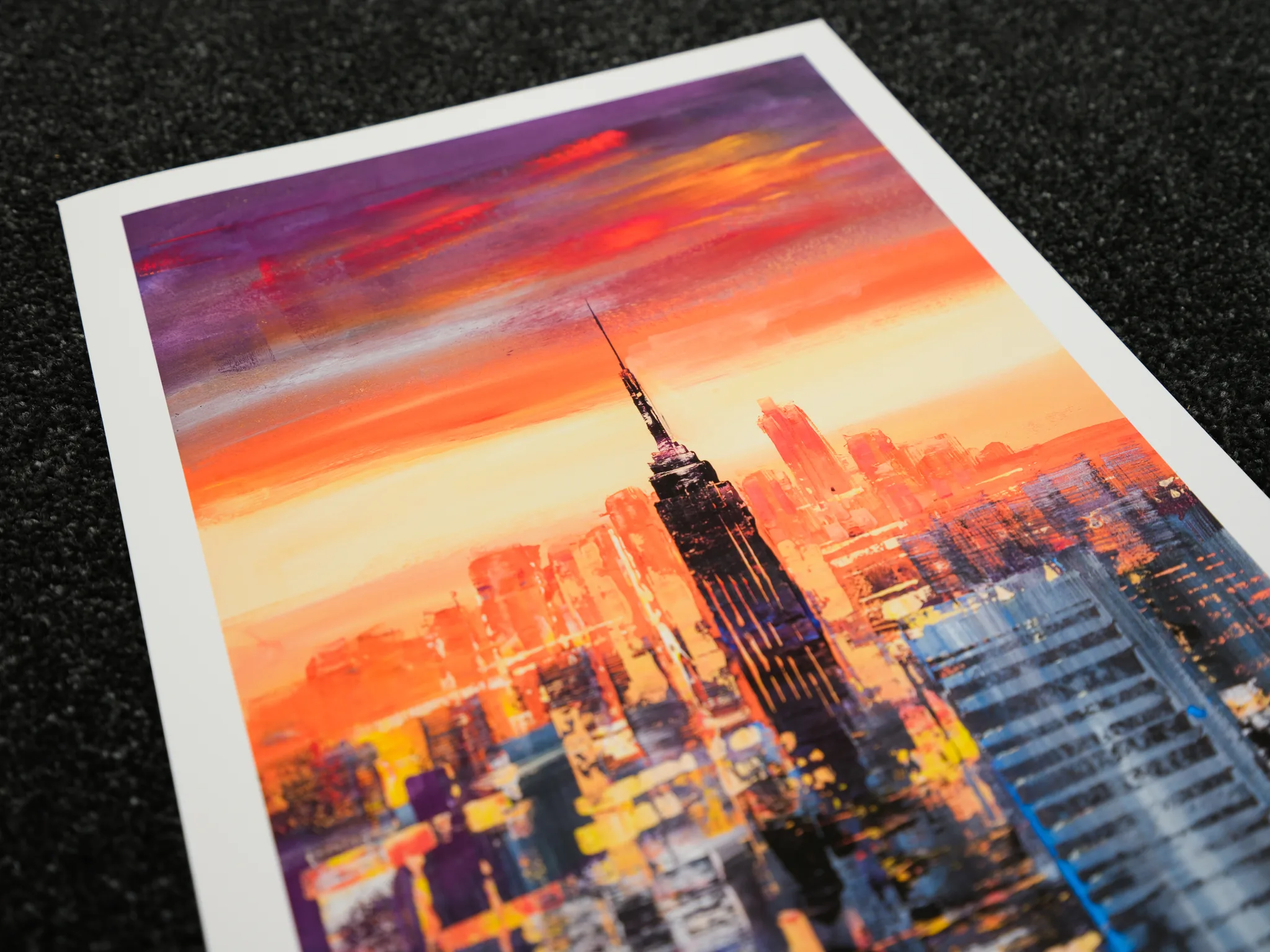 Close-up of Empire State Power, a limited edition print by Paul Kenton, showing the Empire State Building silhouetted against a fiery orange and purple sunset over a blurred New York skyline.