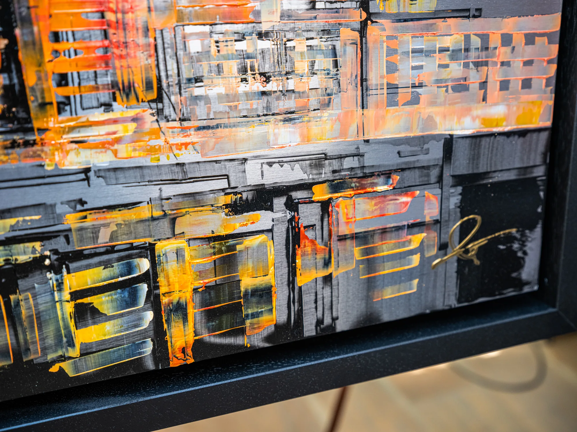 Close-up of Golden Capital, an original painting by Paul Kenton: thick, layered orange and yellow strokes glow over black and grey building forms, with a gold signature in the corner.