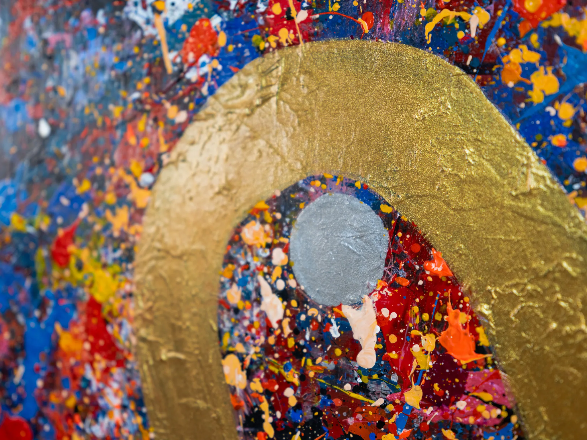 Close-up of Golden Flowing Thames, an original mixed media painting by Paul Kenton: a thick gold arch and silver disc over splattered blue, red and yellow paint, with textured brushwork.
