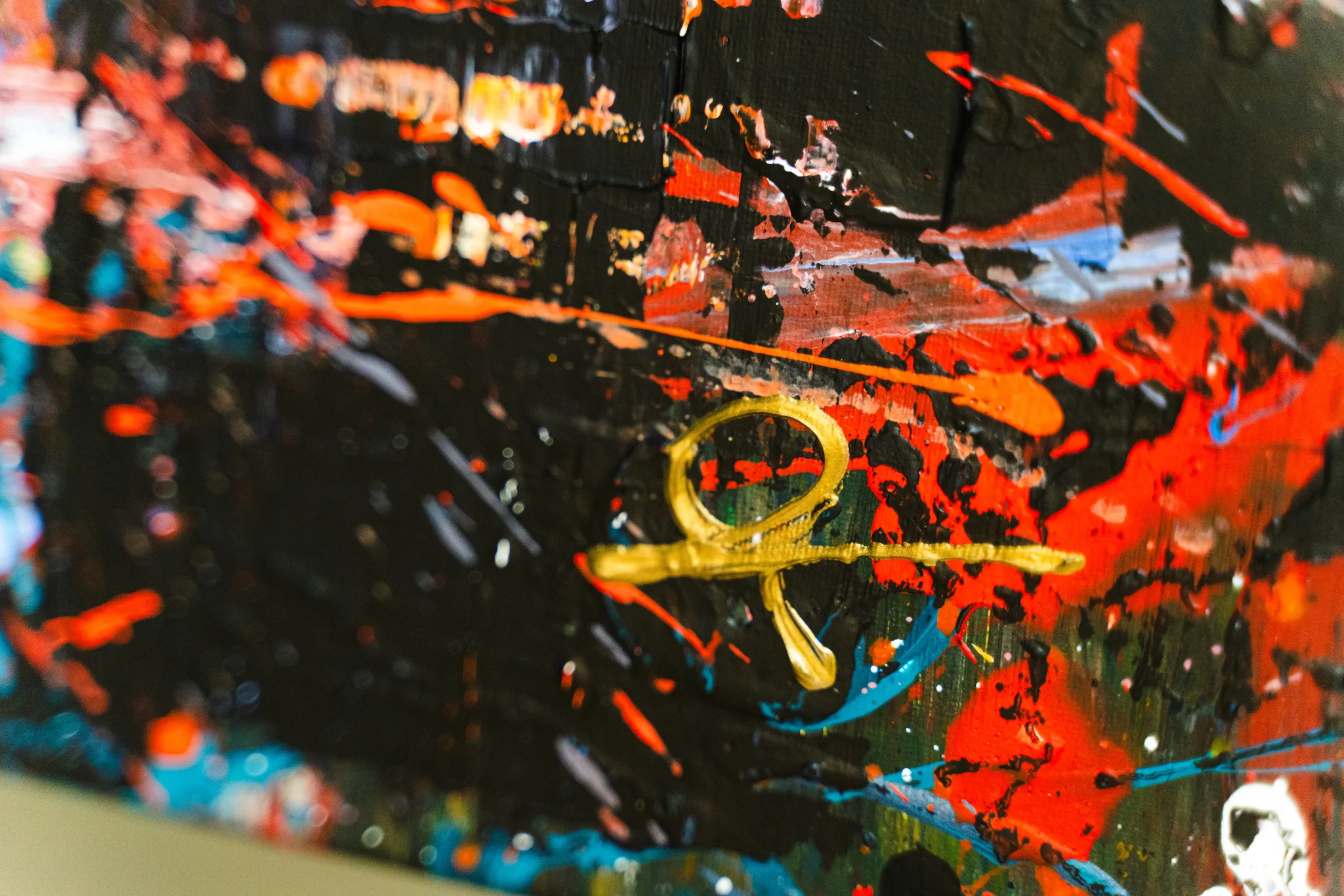 Close-up of London in Motion, an original mixed media painting by Paul Kenton, showing splashes of red, orange and blue over black, with a raised gold ankh-like symbol.