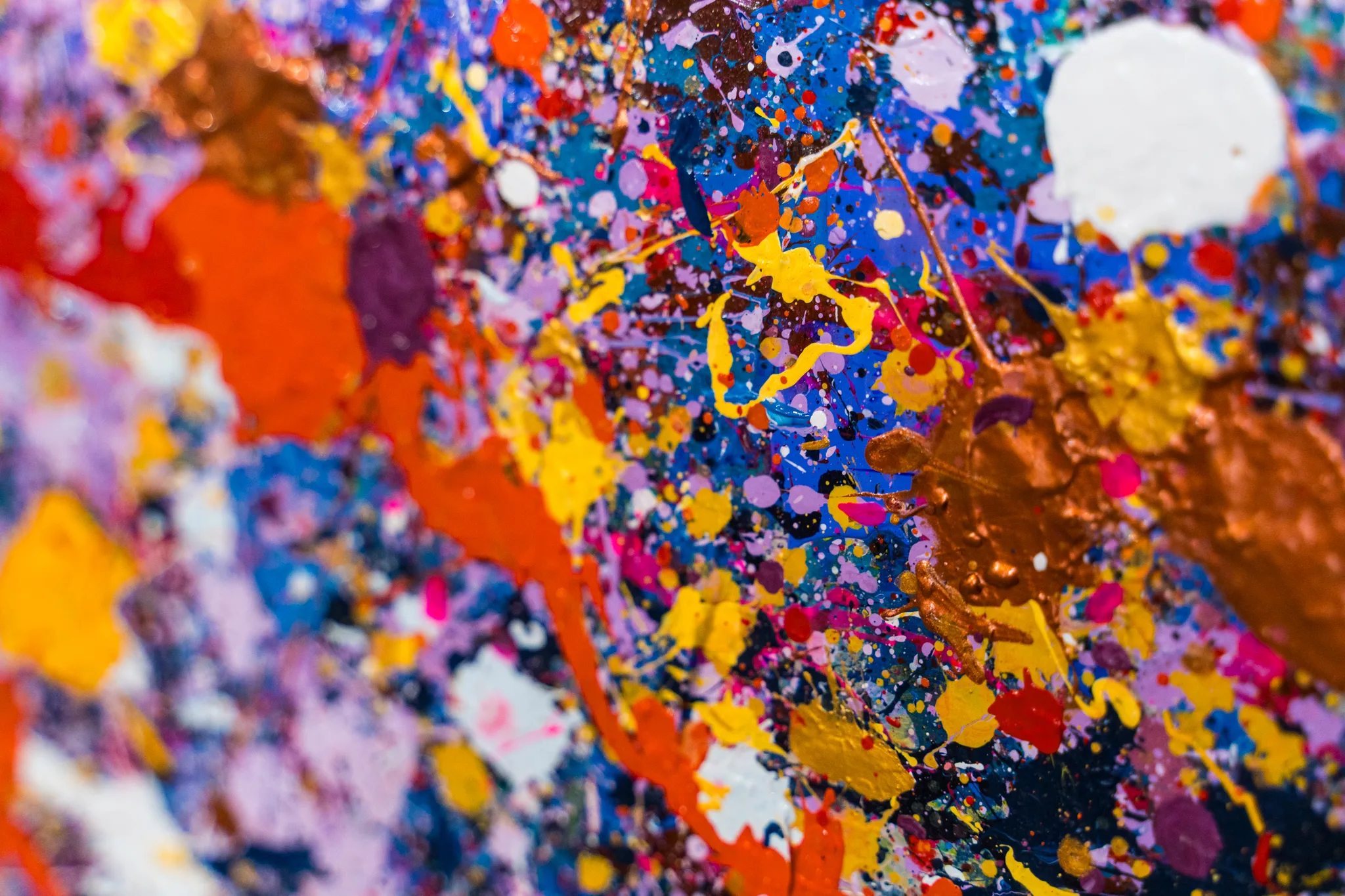 Close-up of Manhattan Burst, an original mixed media painting by Paul Kenton, showing dense splatters of yellow, orange, blue, violet and white paint with copper metallic streaks and bold, textured energy.