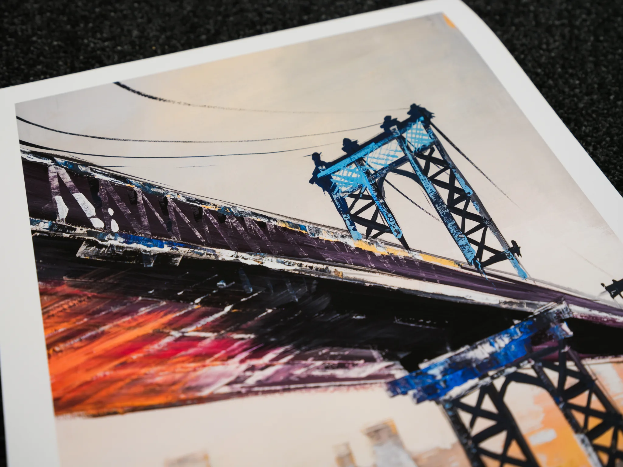 Close-up of a print of Manhattan Bridge Splendour by Paul Kenton, showing blue steel towers and a dark roadway over textured orange and purple brushstrokes.