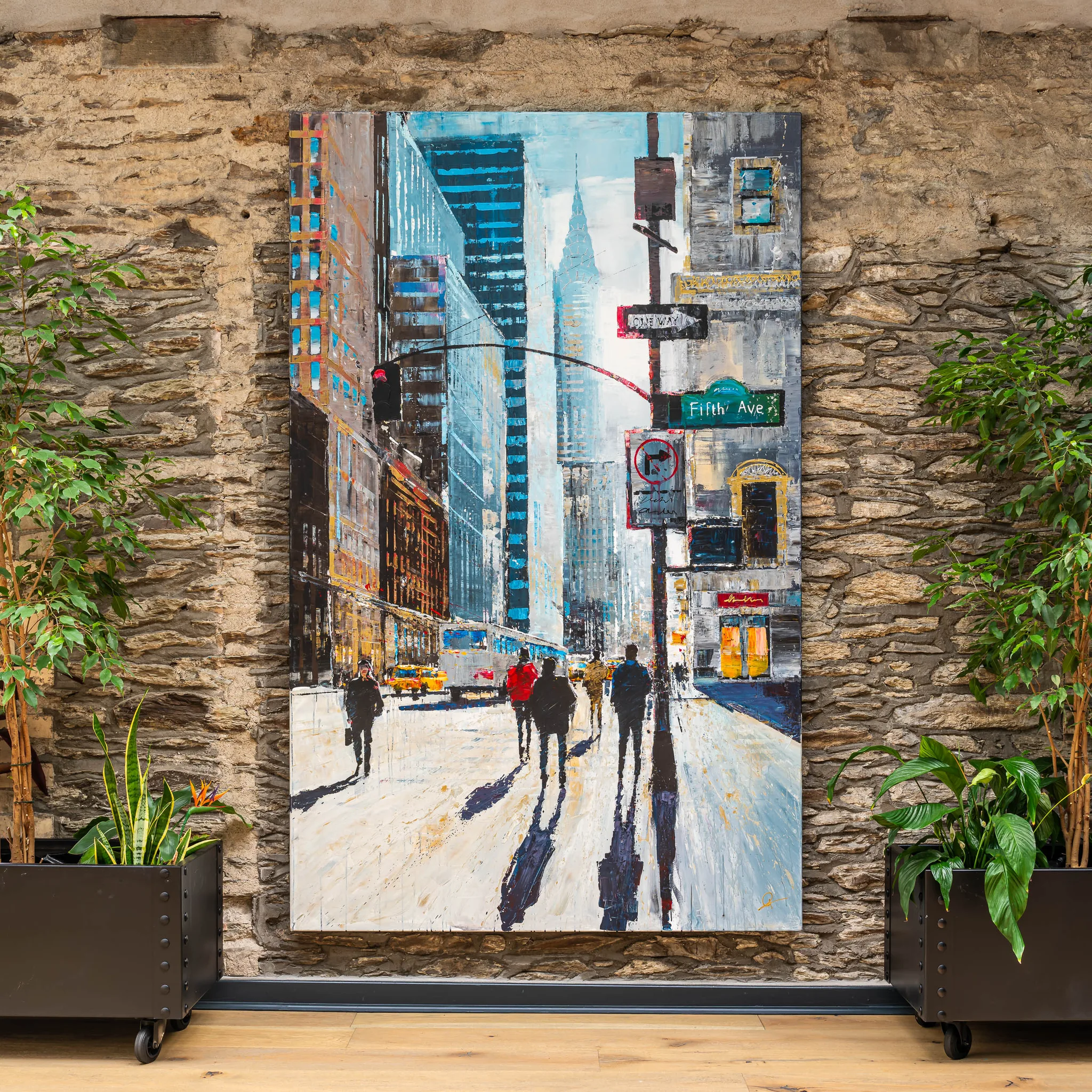 New York Shadows, an original mixed media painting by Paul Kenton hung on a stone wall between potted plants, showing a Fifth Avenue street scene with long shadows of pedestrians on a pale pavement.