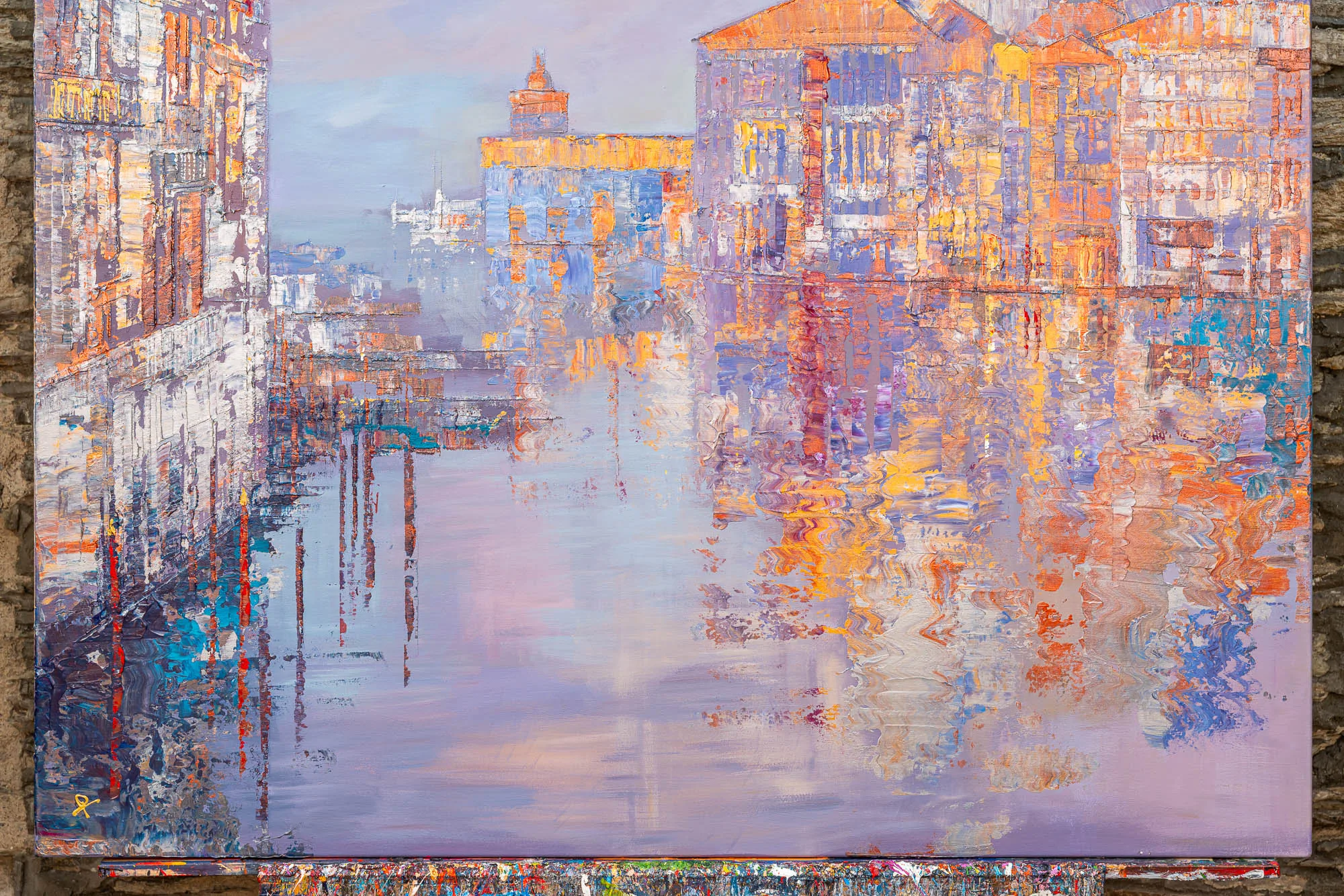 Close-up of Opalescent Venice, an original mixed media painting by Paul Kenton, showing a misty canal lined with thick, textured buildings in lilac, orange and gold, their reflections rippling across pale lavender water.