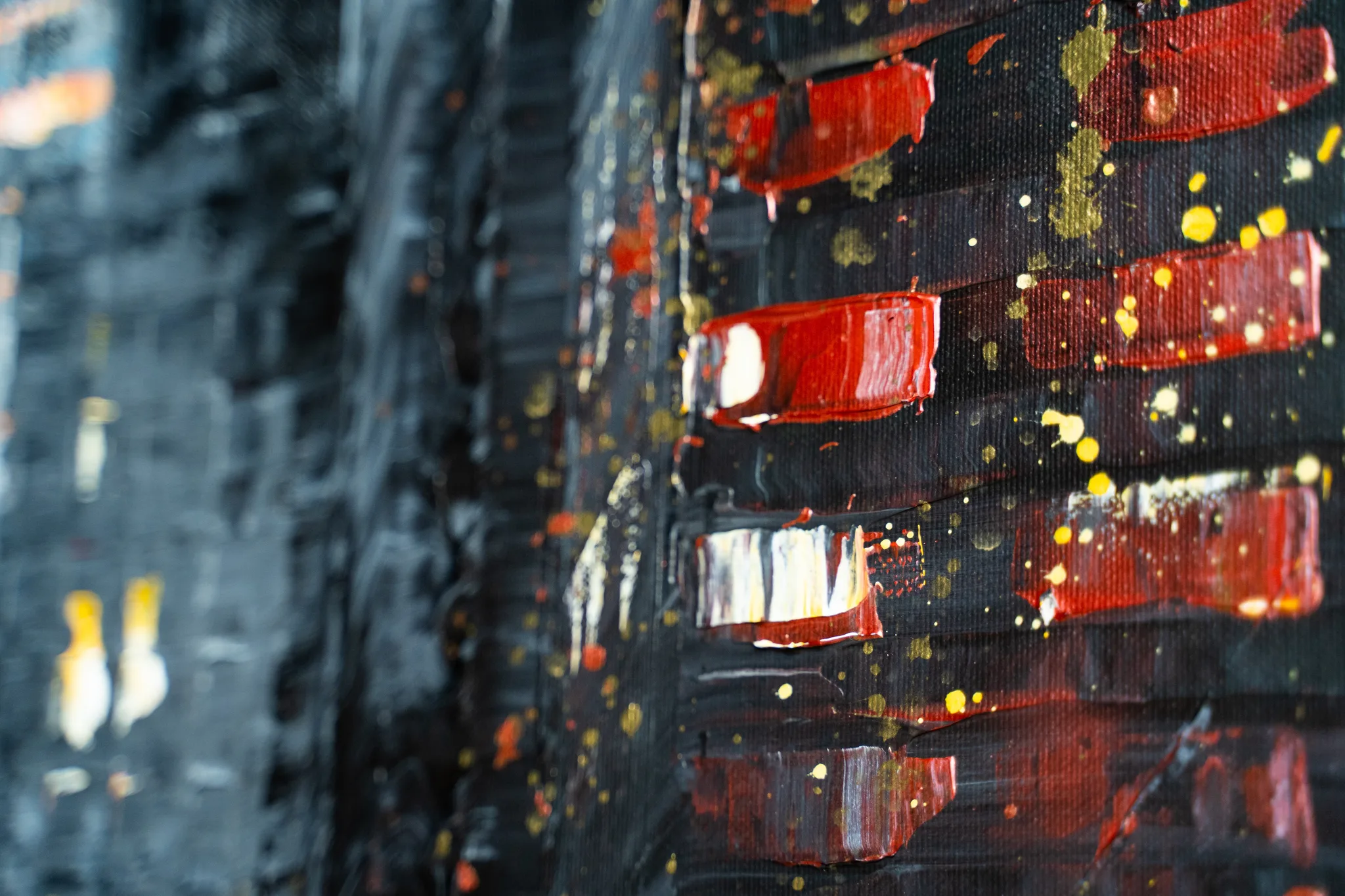 Close-up of Street in Yellow, an original mixed media painting by Paul Kenton, showing thick black and grey textured paint with bold red blocks and flecks of gold and yellow metallic paint.