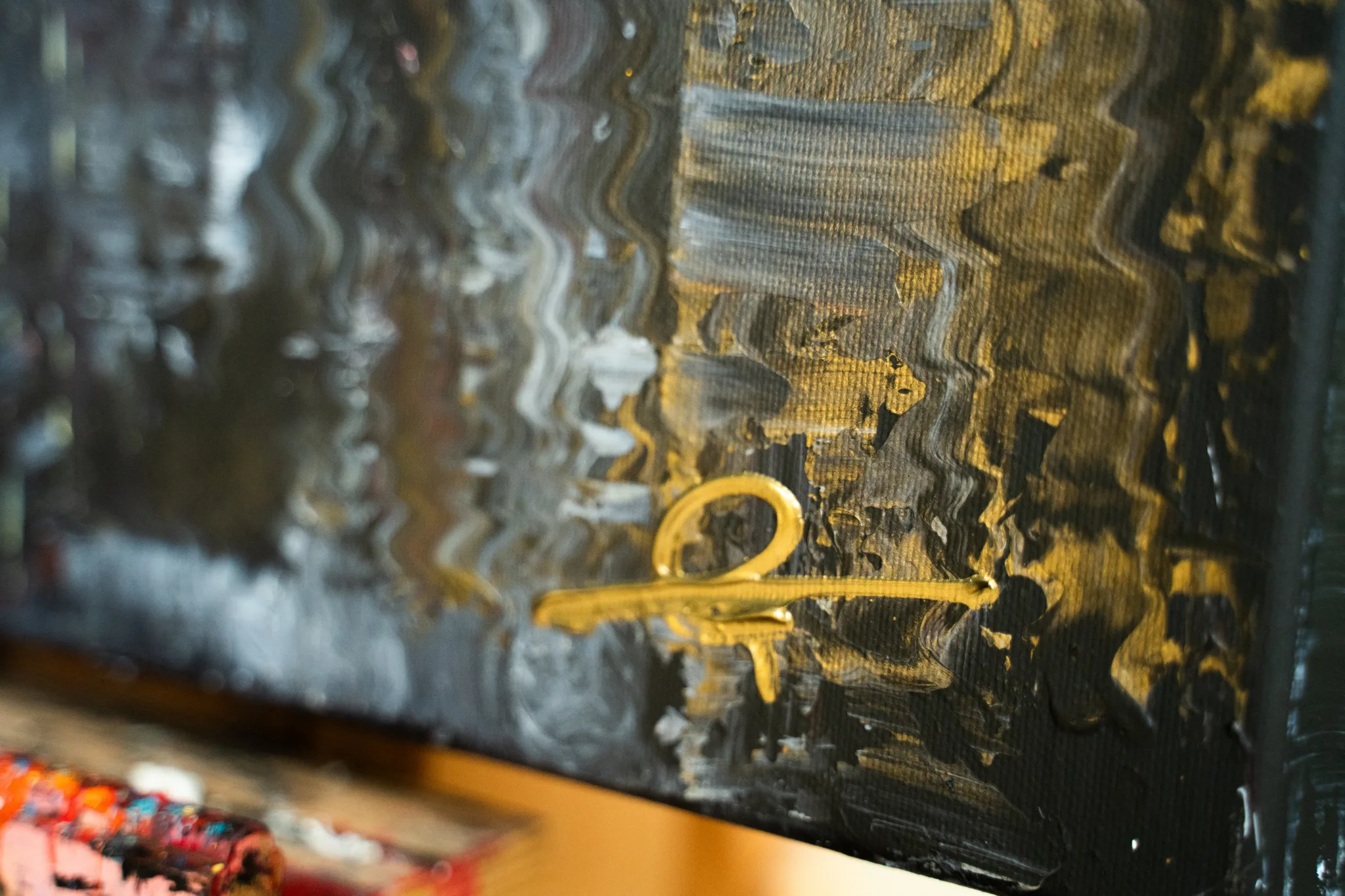 Close-up of Street in Yellow, an original mixed media painting by Paul Kenton: wavy streaks of gold, black and grey paint with a gold signature mark on the canvas.