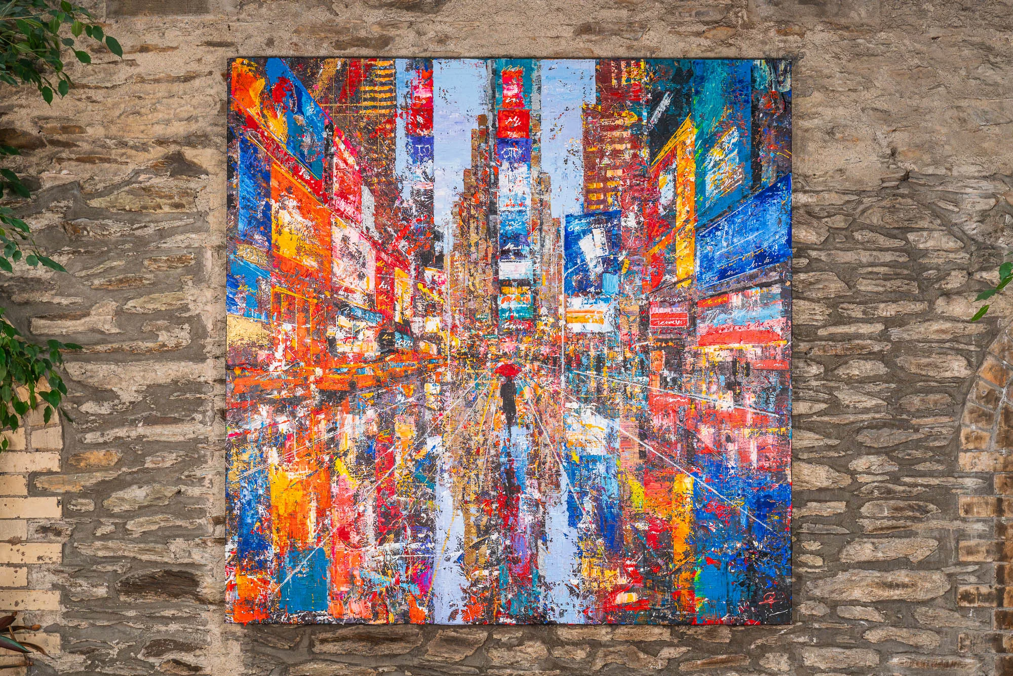 Steps Through Times Square, an original painting by Paul Kenton hung on a stone wall: a bold, textured view down a busy street of red, orange and blue billboards, with a lone figure at the centre.