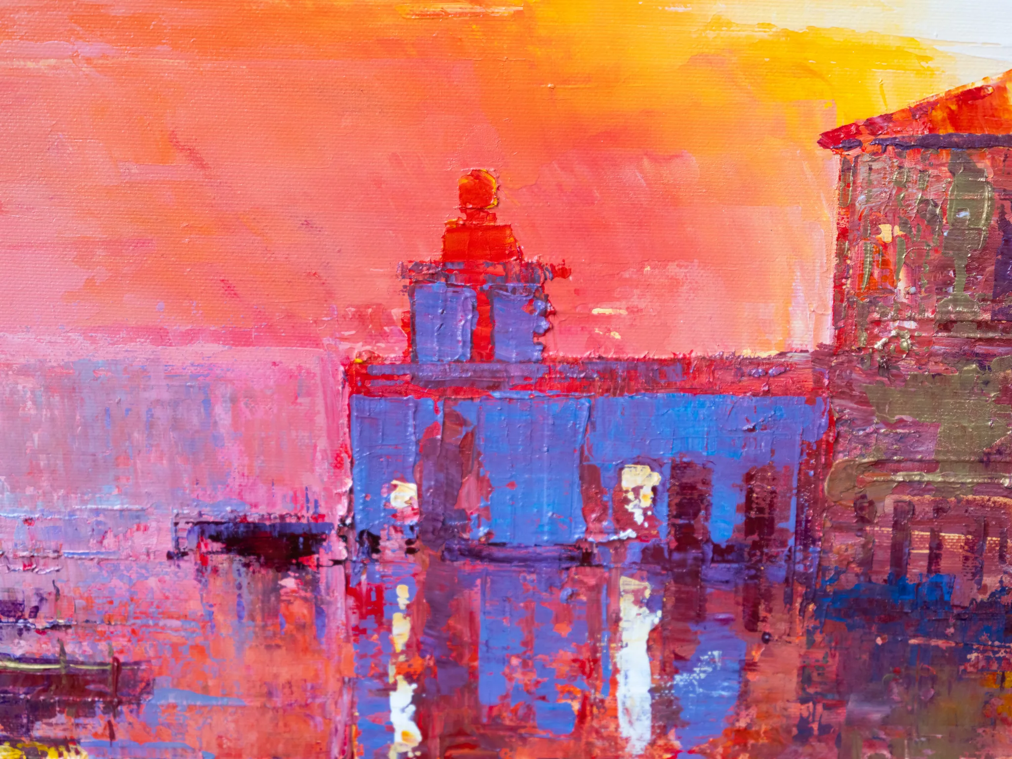 Close-up of Venice Ablaze, an original painting by Paul Kenton, showing thick textured brushwork: a blue canal-side building glowing against a fiery orange and pink sunset sky, with rippling red reflections in the water.