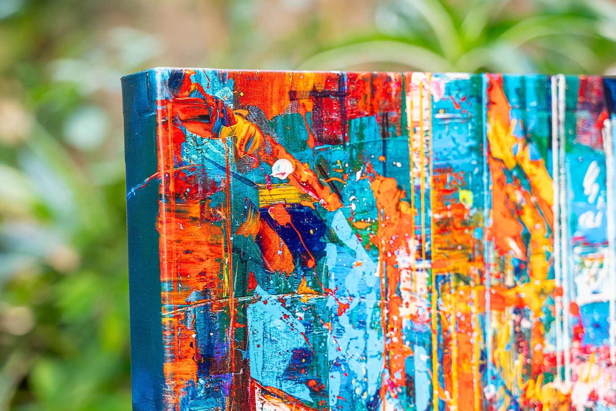 Close-up of the corner of Fairytale Of New York, a limited edition print on boxed canvas, showing bold orange, red, blue and yellow brushwork with dripping paint and textured layers.