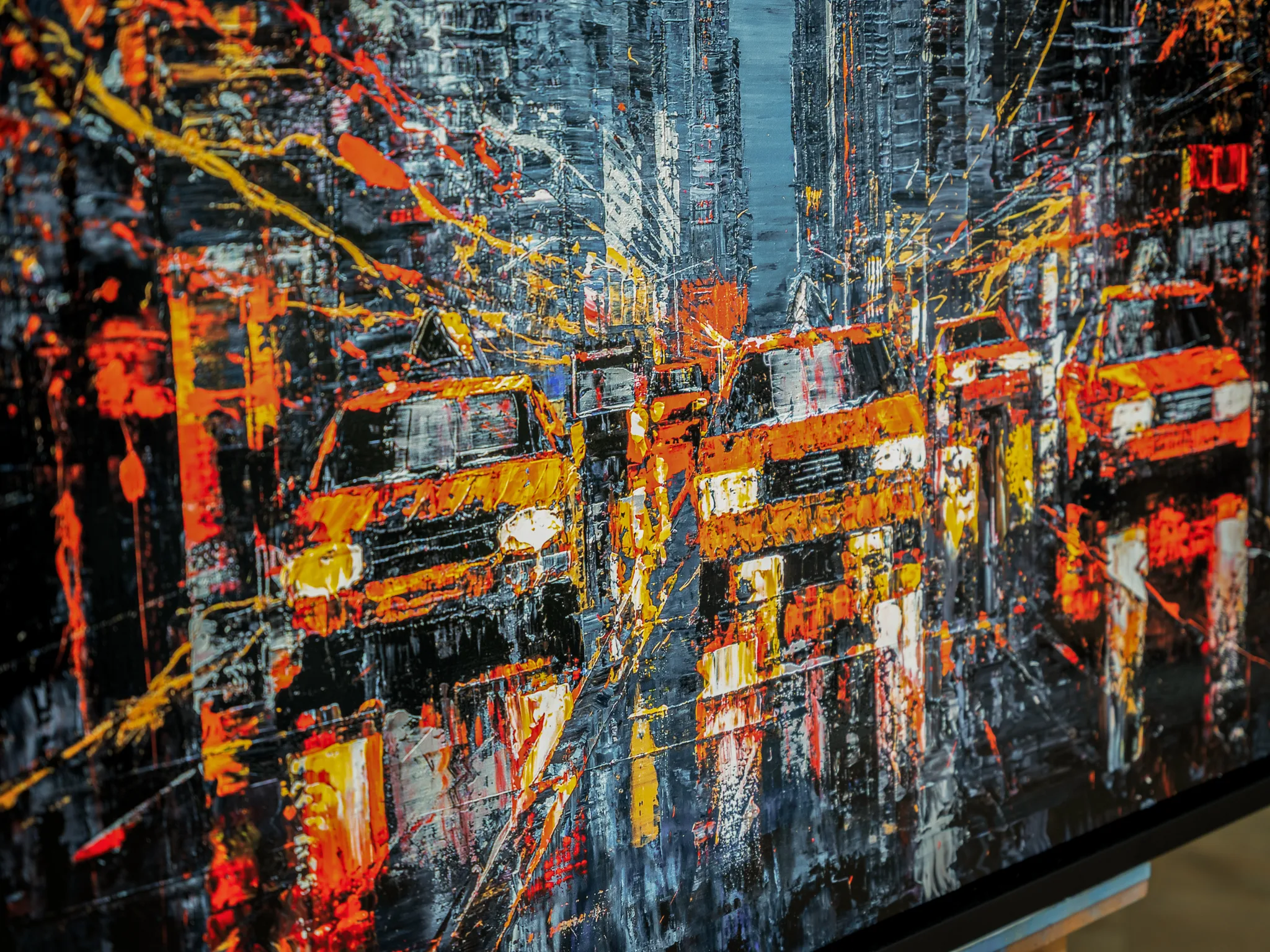 Close-up of Flight of the Taxis, a limited edition print by Paul Kenton, showing thick textured orange and yellow taxi shapes and dark city towers in New York, with bold splashes of paint.