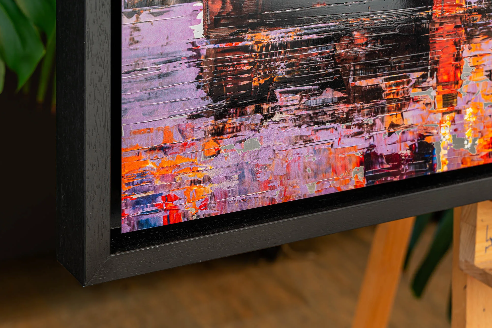 Close-up of London Ablaze, a limited edition print by Paul Kenton, showing thick textured streaks of violet, orange and red across a dark, glossy surface, with a black frame edge.