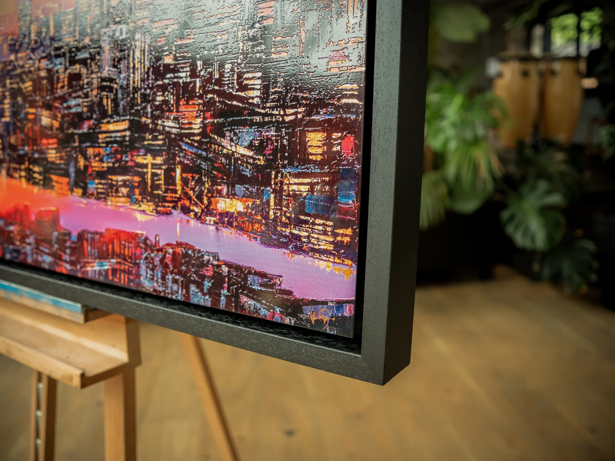 Close-up of London Embers, a limited edition print by Paul Kenton, showing a dense night cityscape of glowing windows and a pink-violet river in textured, embellished detail, within a dark grey frame.