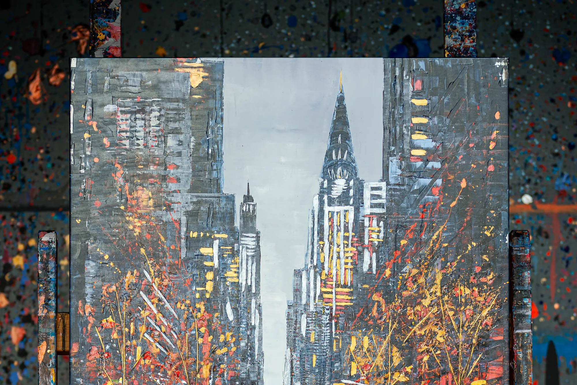 Close-up of New York Serenade, an embellished giclée print on canvas by Paul Kenton, showing a grey Manhattan street with a spired skyscraper and warm orange and gold splashes of autumn colour.