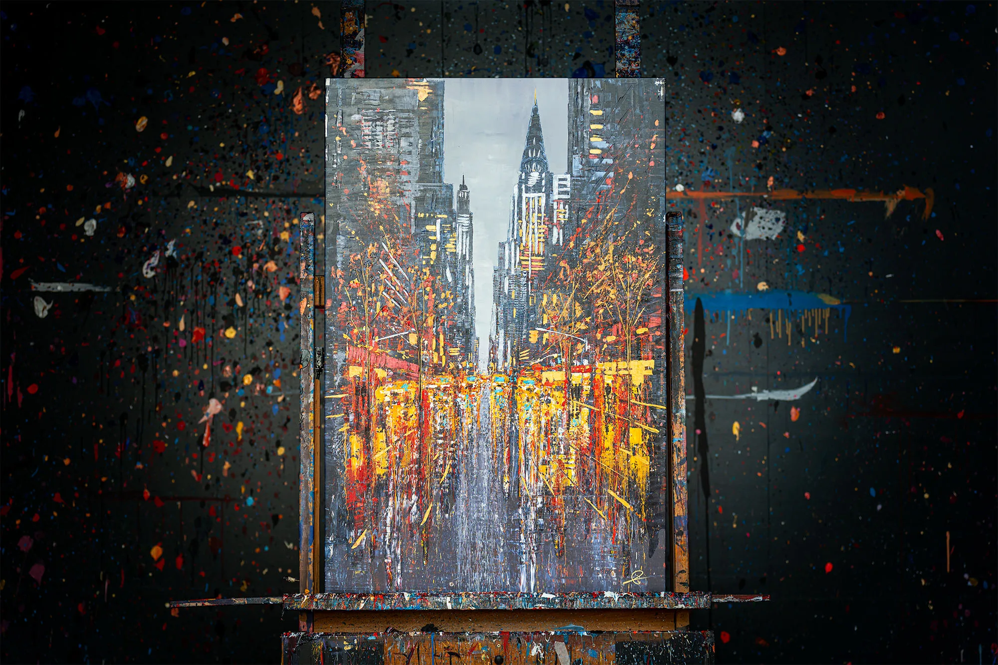 New York Serenade, a limited edition print on an easel, its glowing gold street beneath a spired skyscraper, against a paint-splattered wall.
