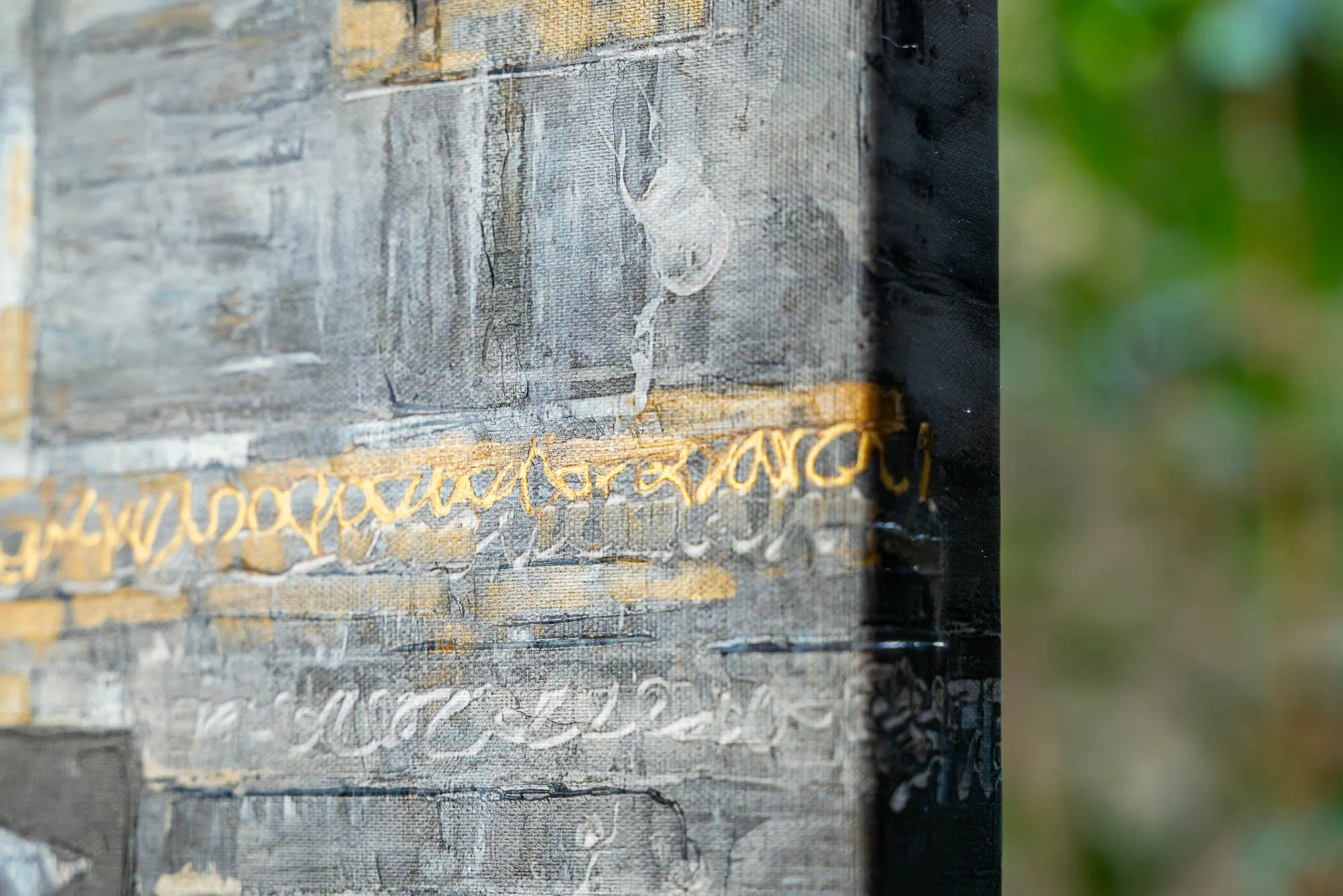 Close-up of New York Shadows, a limited edition print by Paul Kenton, showing textured grey and black surfaces with gold and white looping script marks and the edge of the boxed canvas.