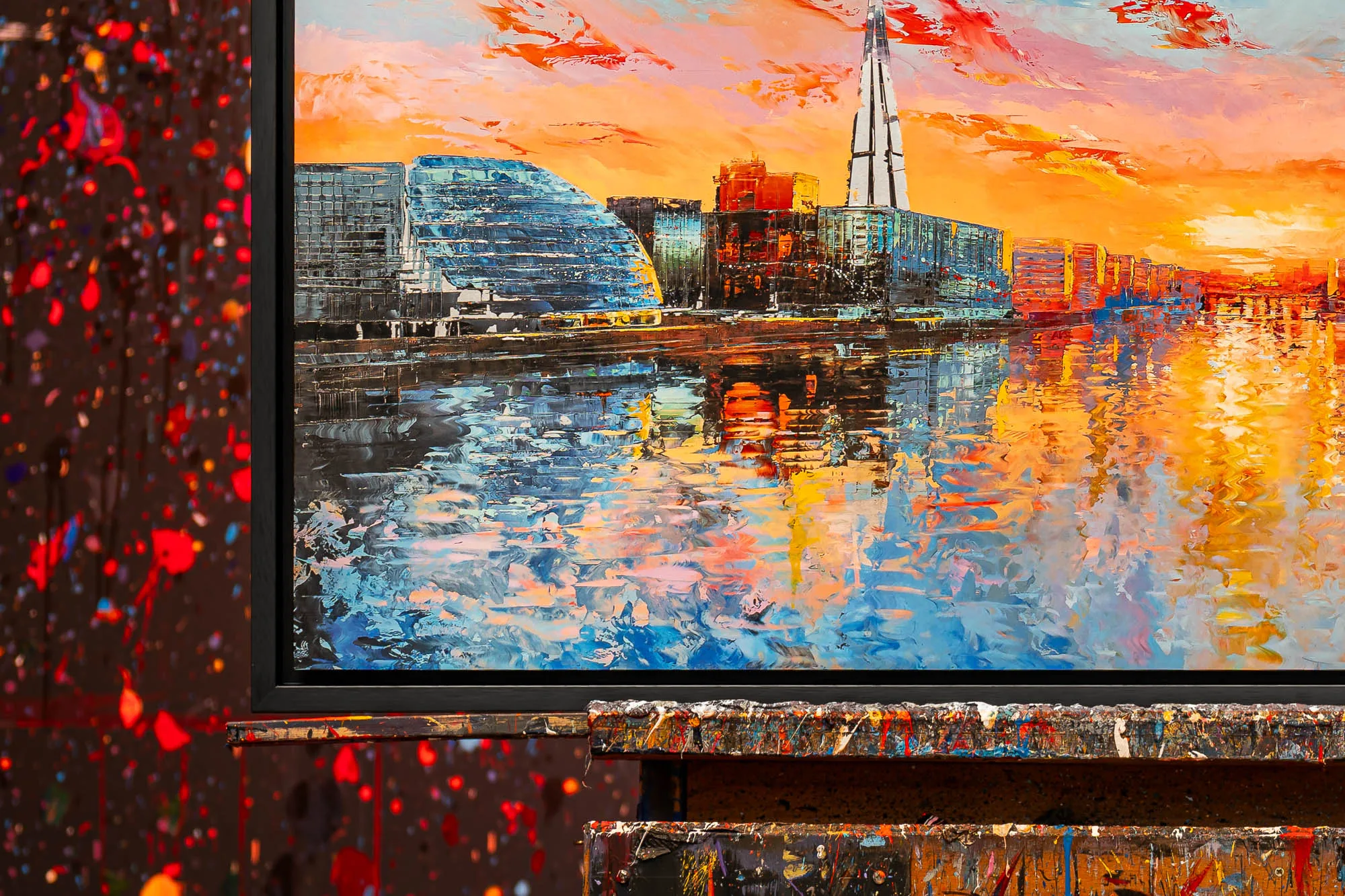 Close-up of Panoramic Glow, a limited edition print by Paul Kenton: thick textured brushwork shows a London waterfront at sunset, orange sky, blue buildings and a tall spire reflected in water.