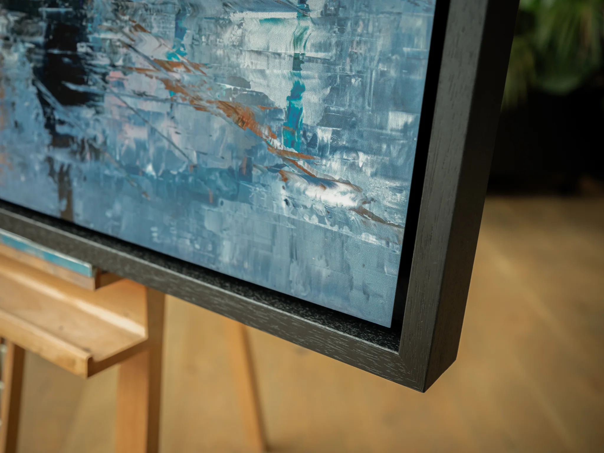 Close-up of the lower corner of Thames Light, a limited edition print by Paul Kenton, showing textured blue and grey brushwork with copper streaks and a dark black frame.