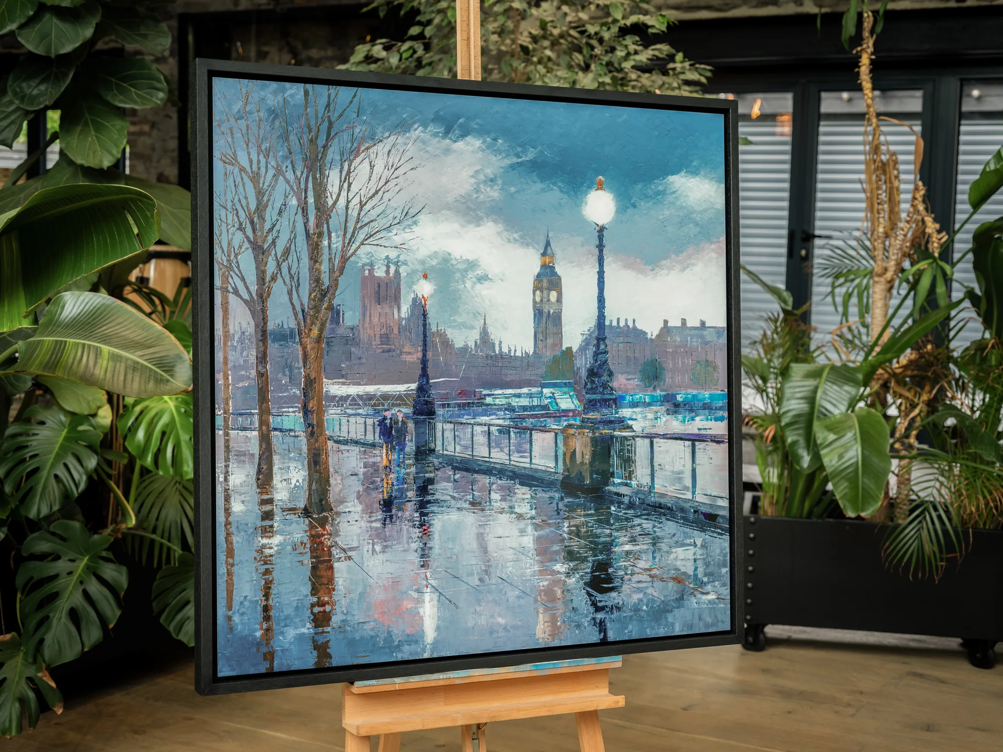 Thames Light, a limited edition print in a black frame on an easel among green plants, shows Big Ben above a rain-slicked riverside path.