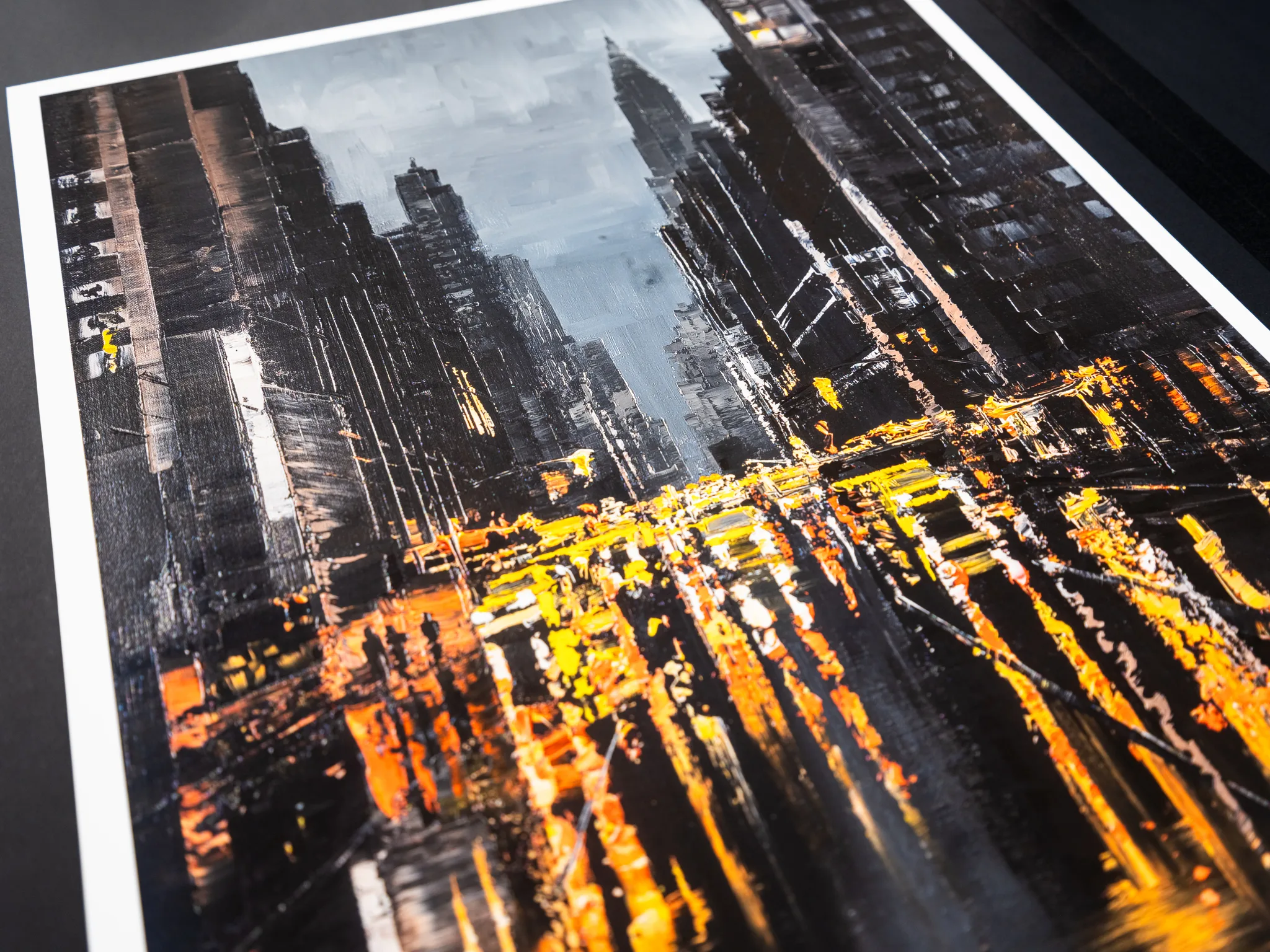 Close-up of Manhattan Glow, a limited edition print by Paul Kenton, showing a textured view down a New York street, with dark, grey skyscrapers, a pale blue sky and warm amber and orange light glowing across the road.