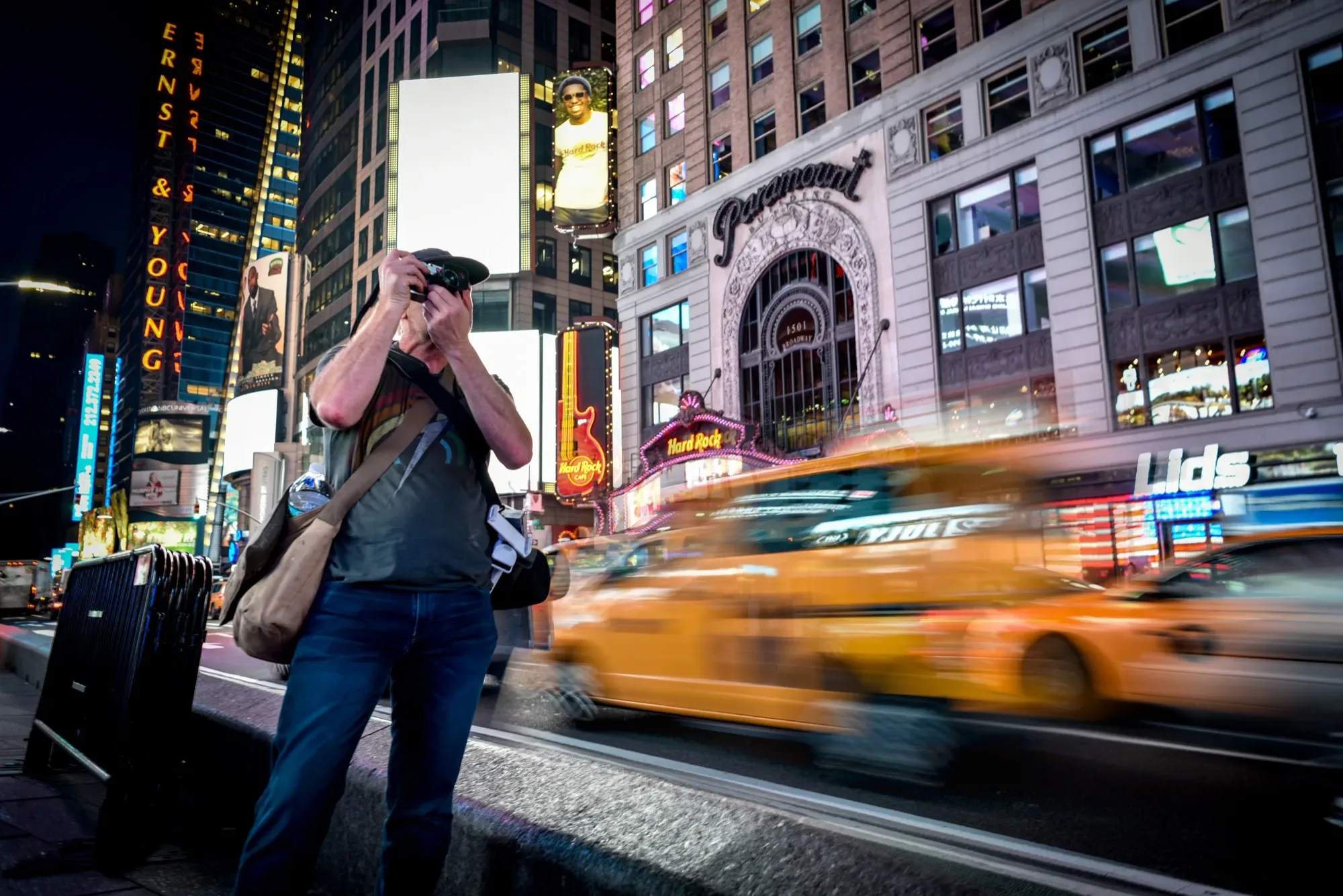 Paul Kenton photographing Times Square at night as yellow cabs blur past the lit-up Paramount building