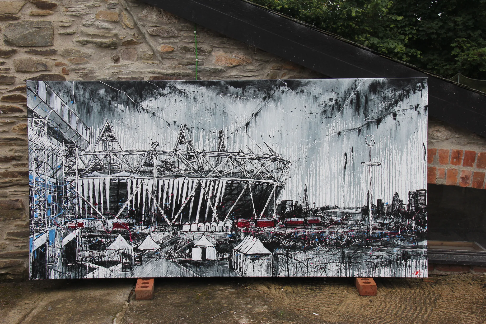 The finished London Glory canvas propped on bricks against a stone wall outdoors