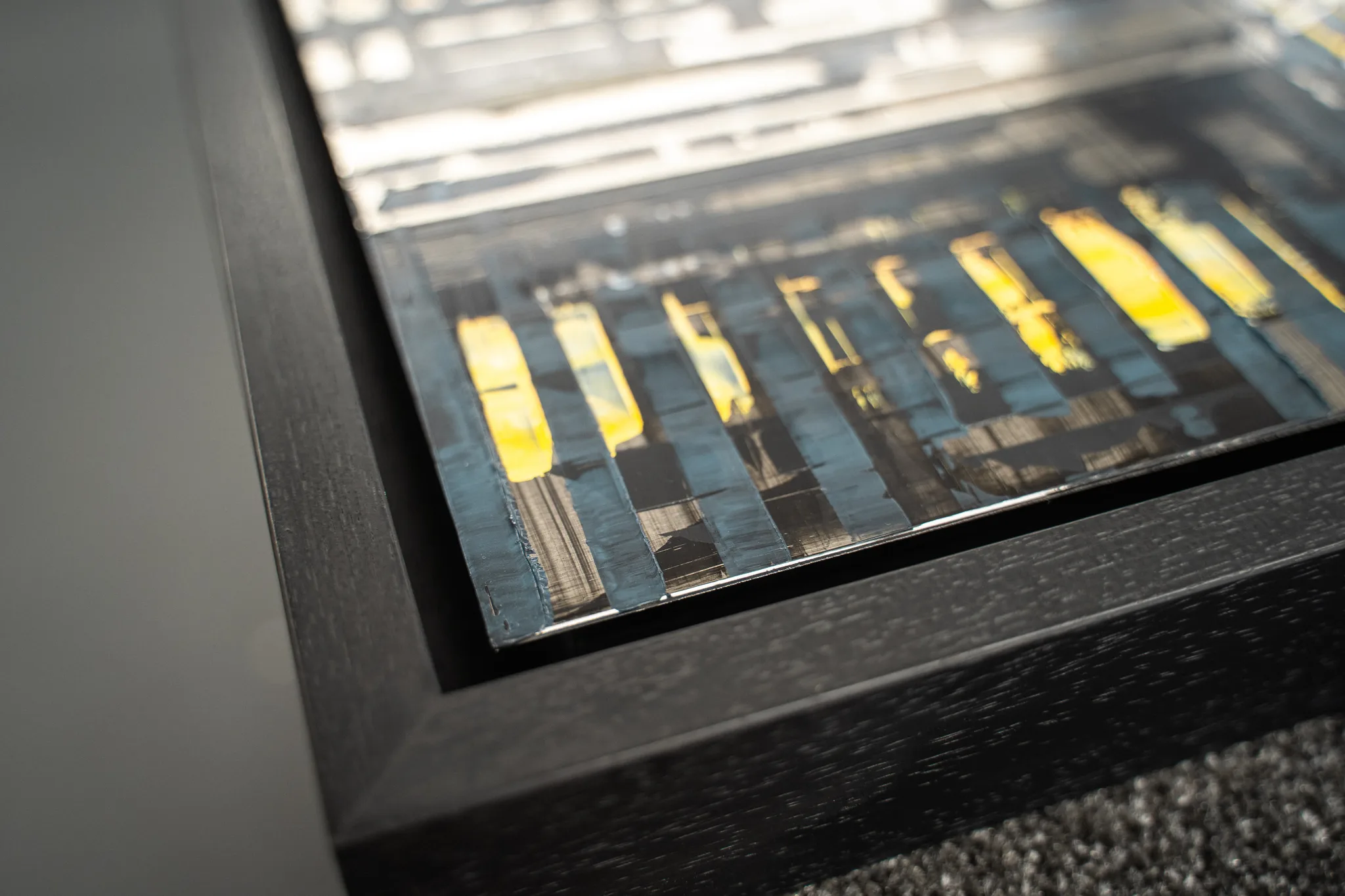 Close-up of a black floating frame, with a narrow gap between the frame and the edge of a cityscape on aluminium