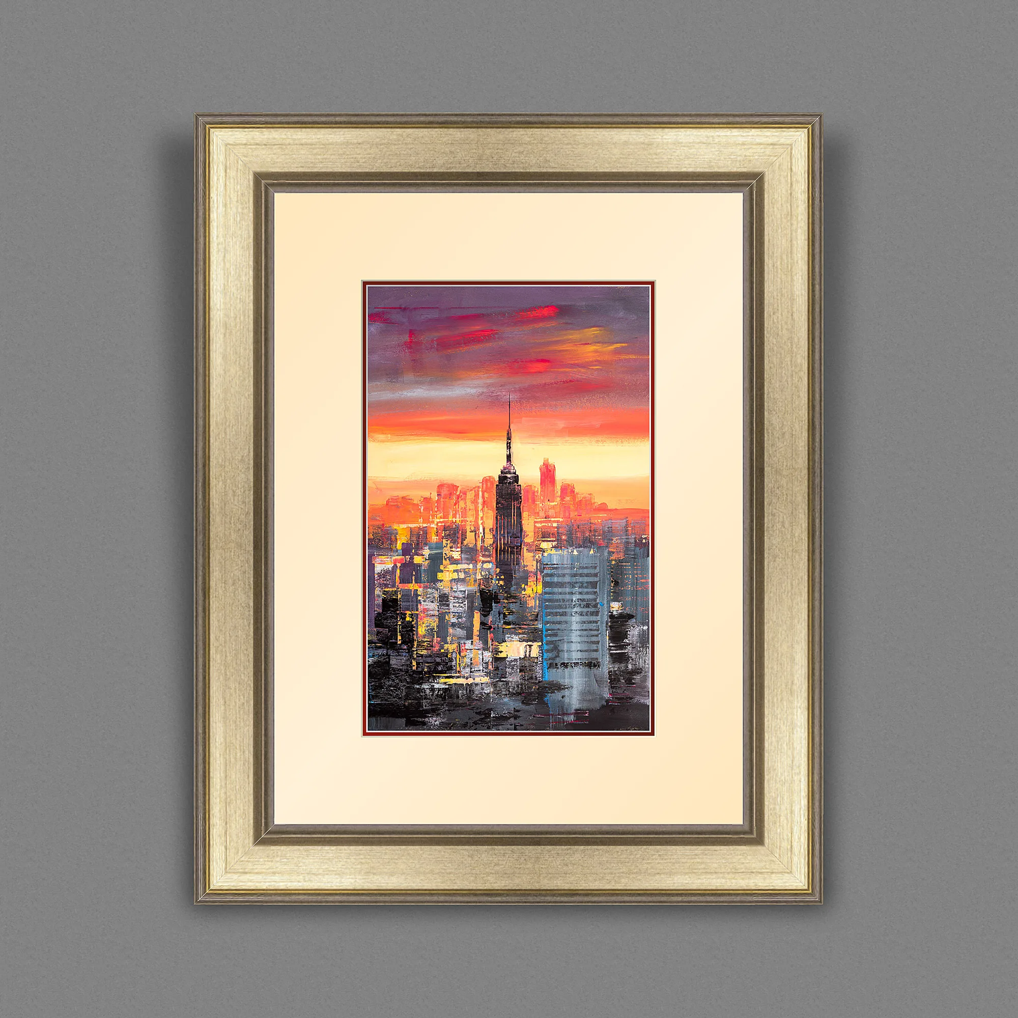 Empire State Power, a limited edition print by Paul Kenton shown in a silver-gold frame with a cream mount: a sunset New York skyline with the Empire State Building glowing orange and red above dark towers.