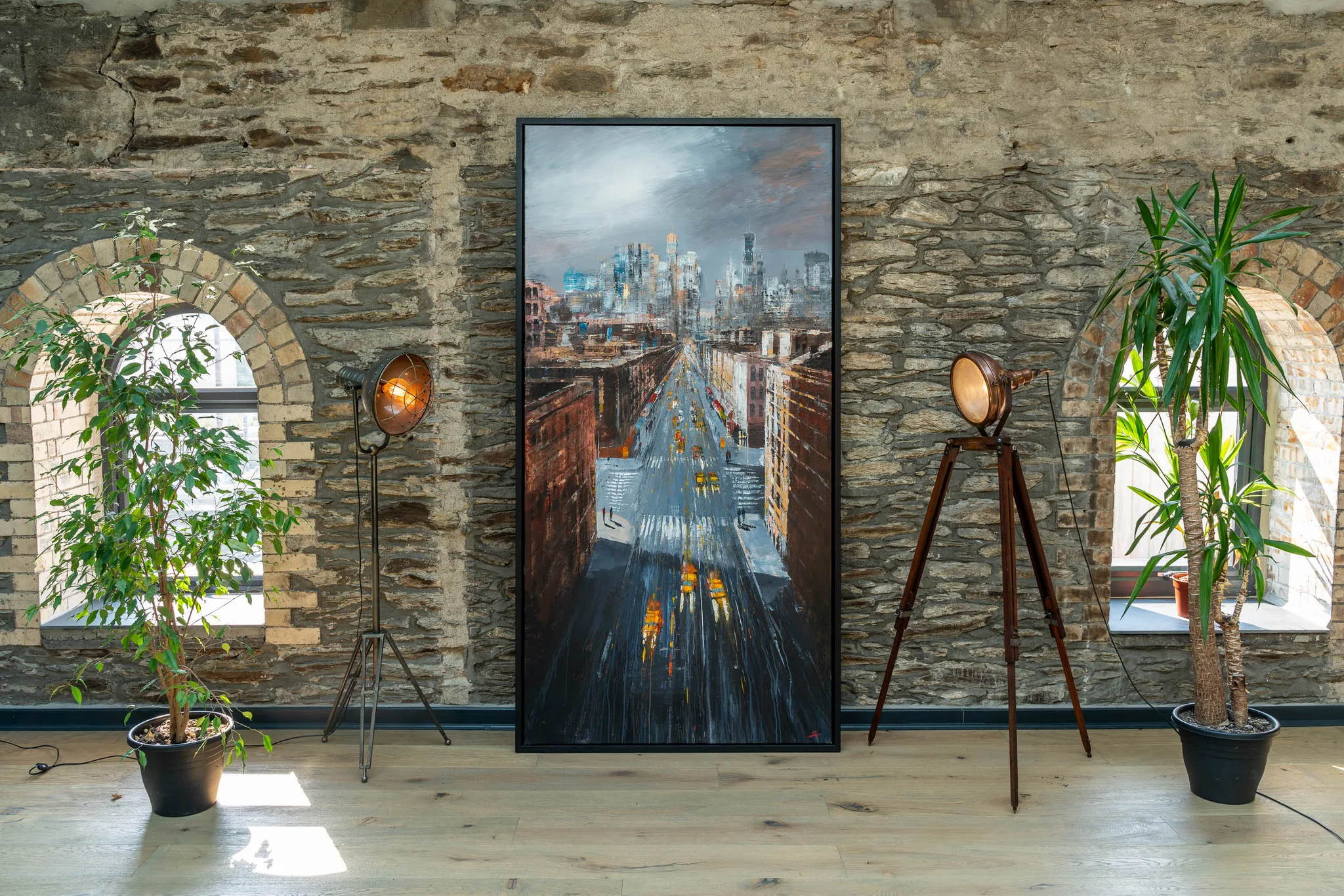 New York Groove, an original painting by Paul Kenton: a rain-slicked city street glowing warm beneath a grey skyline, hung in a stone-walled room.