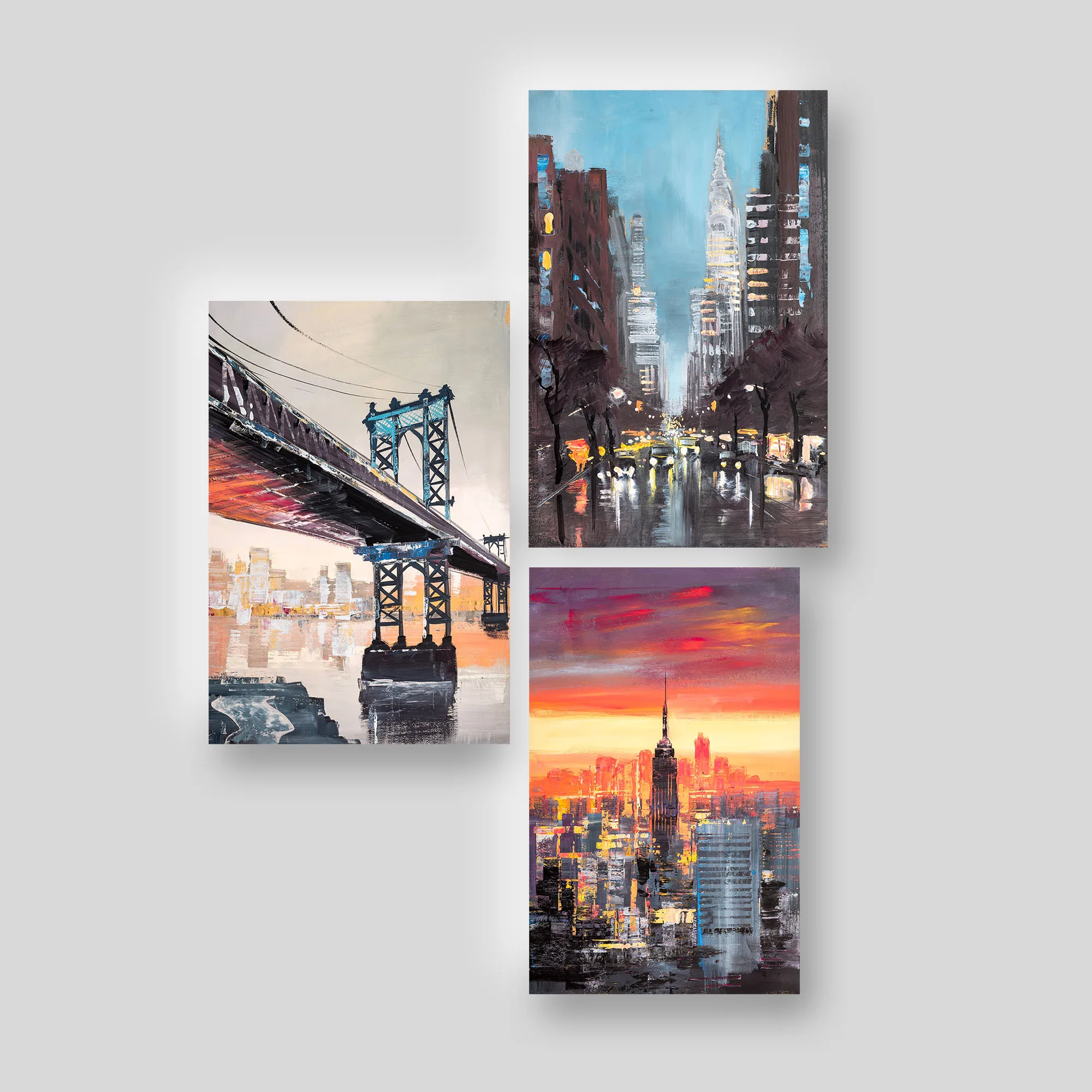 New York Landmarks, a set of three prints by Paul Kenton: the Manhattan Bridge at dusk, a rain-slicked street beneath the Chrysler Building, and the Empire State Building above a fiery sunset skyline.