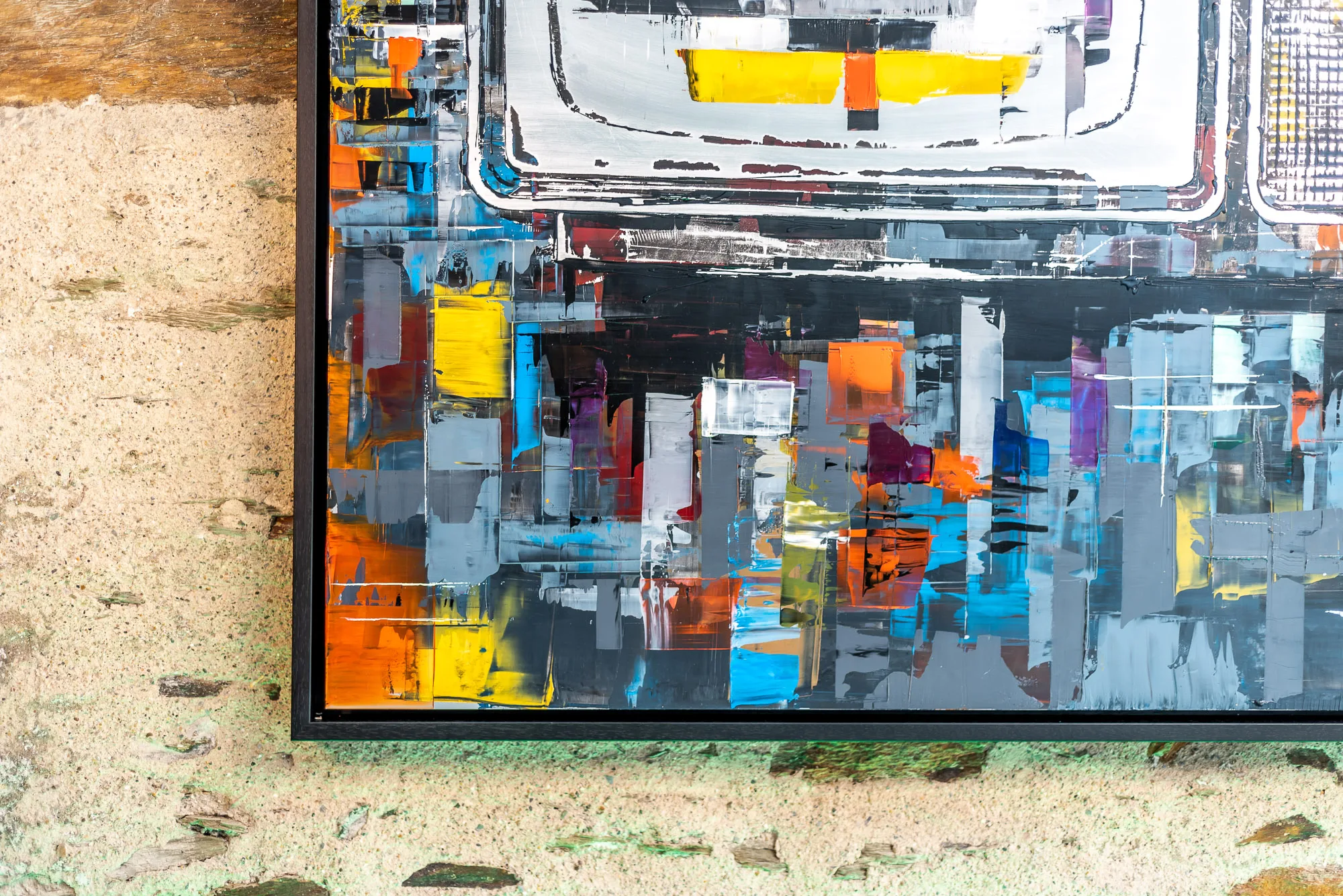 Close-up of the lower corner of Test Card TV, an original mixed media painting on aluminium by Paul Kenton, showing thick palette-knife strokes in yellow, orange, blue and grey over black, with a black frame edge.